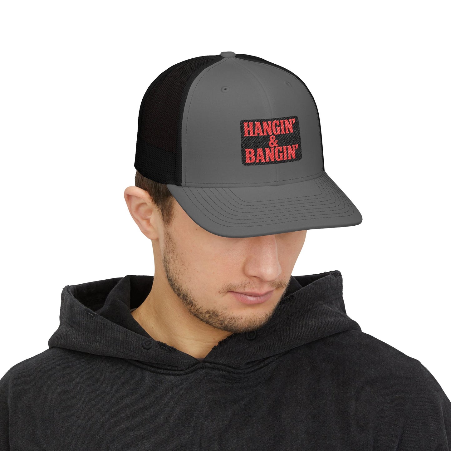 Hangin’ & Bangin’ patch hat resting on metal jobsite toolbox – tough workwear snapback for blue collar workers