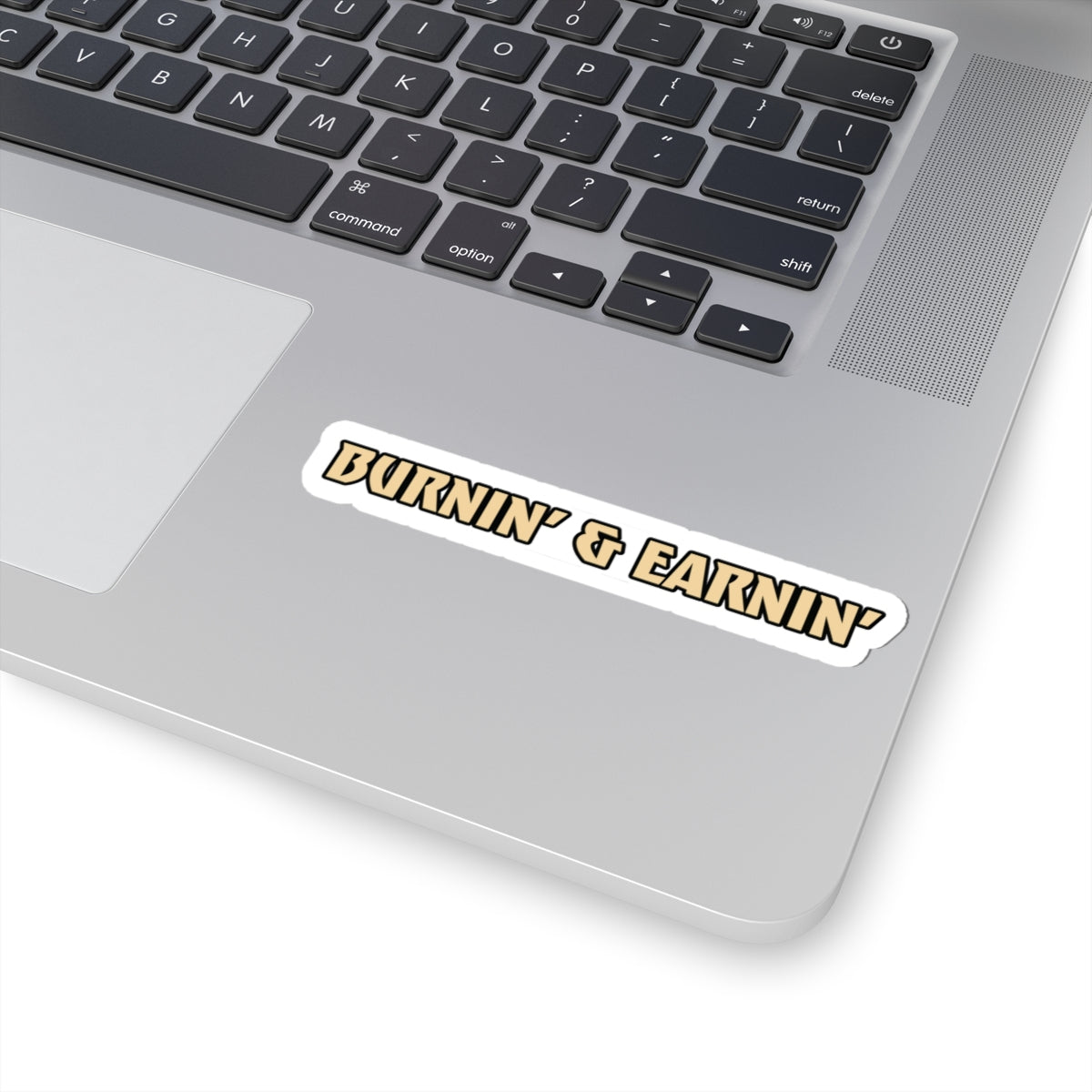 Laptop with a sticker reading 'Burnin' & Earnin'' on a white background