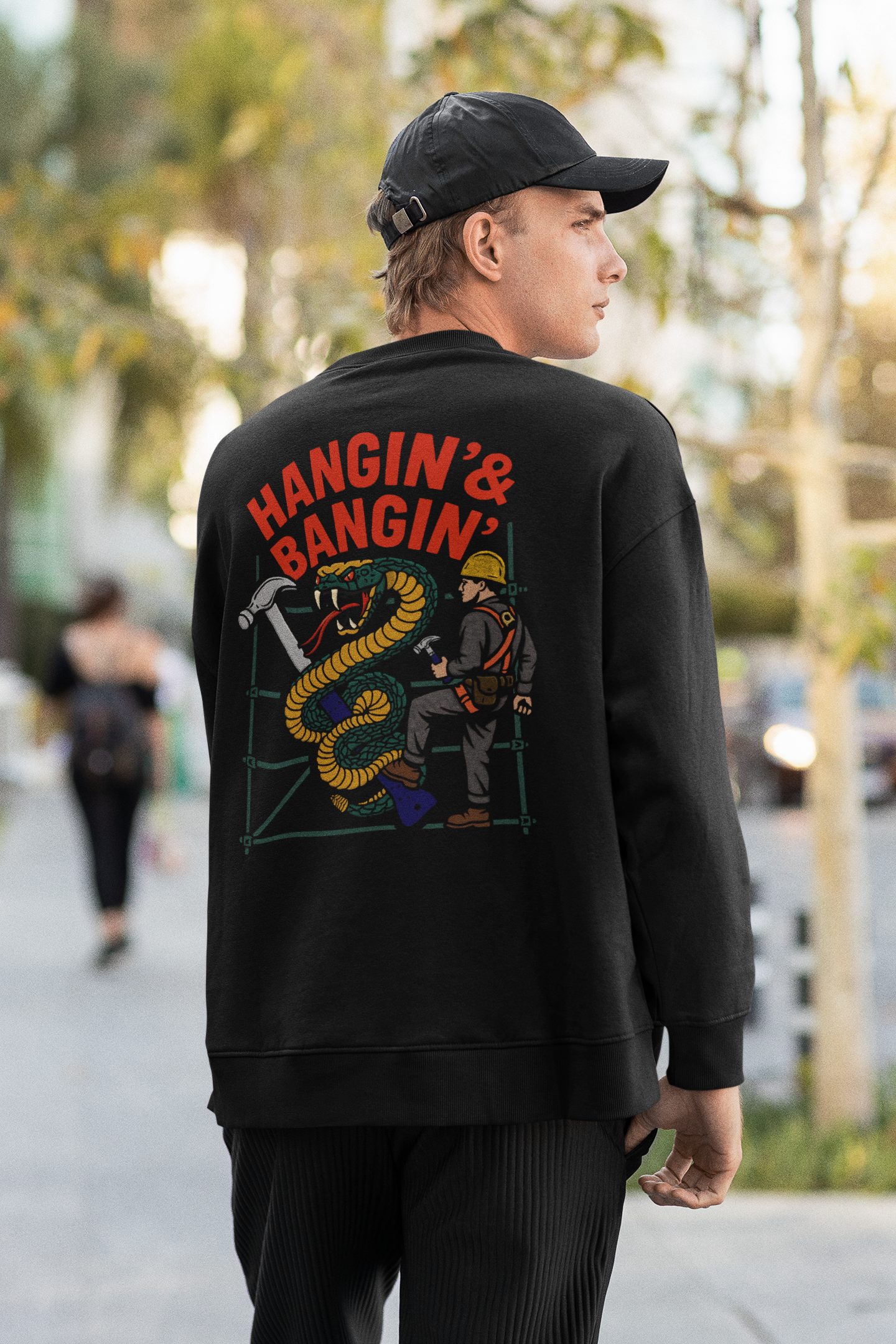 Model wearing black crewneck with Hangin’ & Bangin’ full back graphic featuring scaffolder and snake

