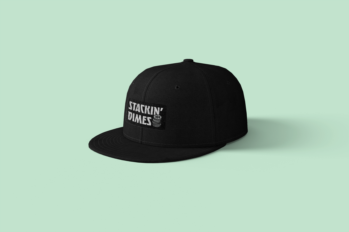 Black cap with 'Stackin' Dimes' logo on a light green background