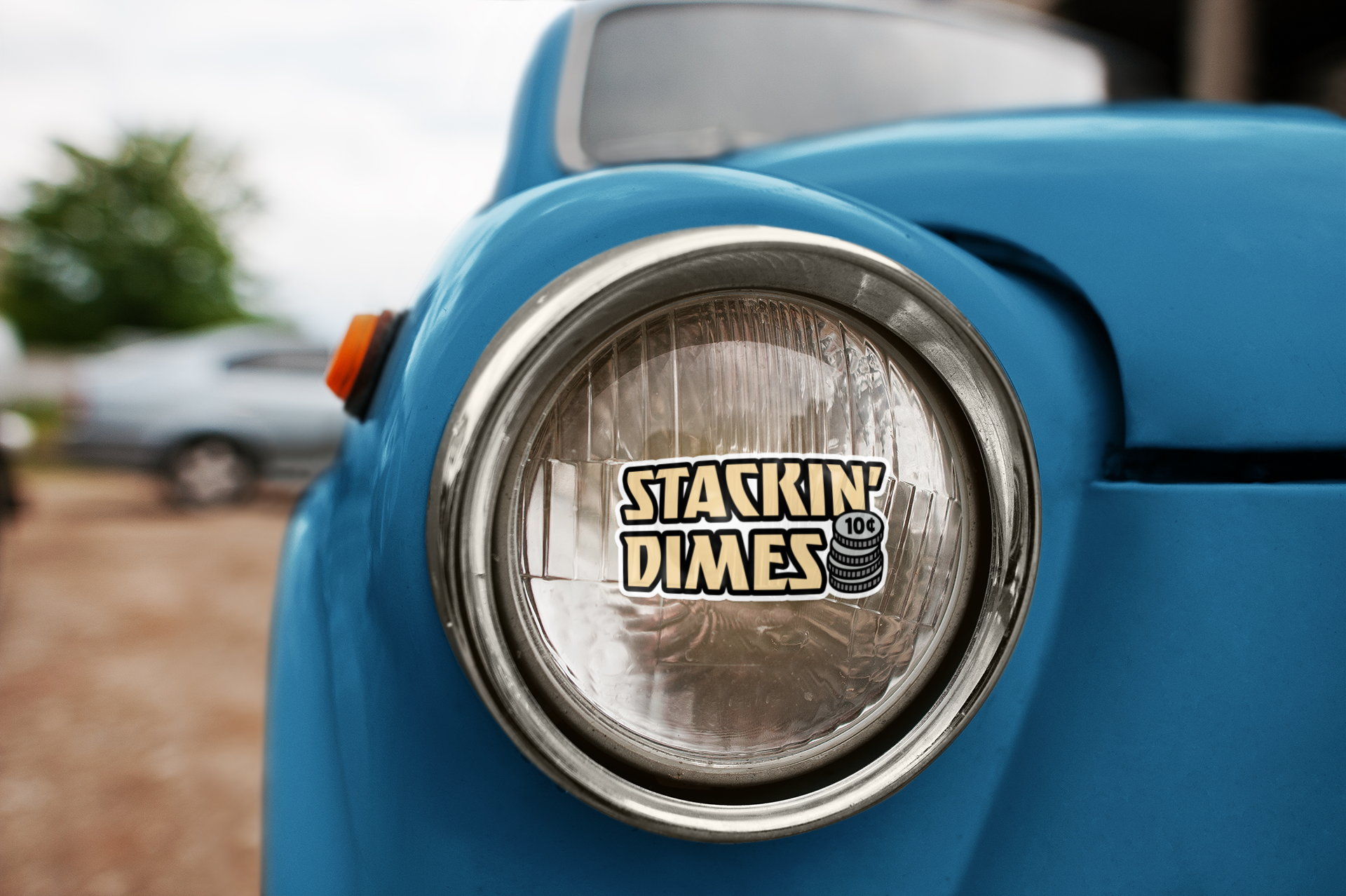 Close-up of a blue vehicle's headlight with 'Stackin' Dimes' logo.