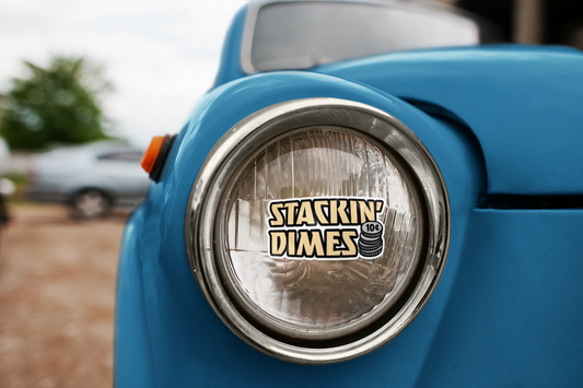 Close-up of a blue vehicle's headlight with 'Stackin' Dimes' logo.