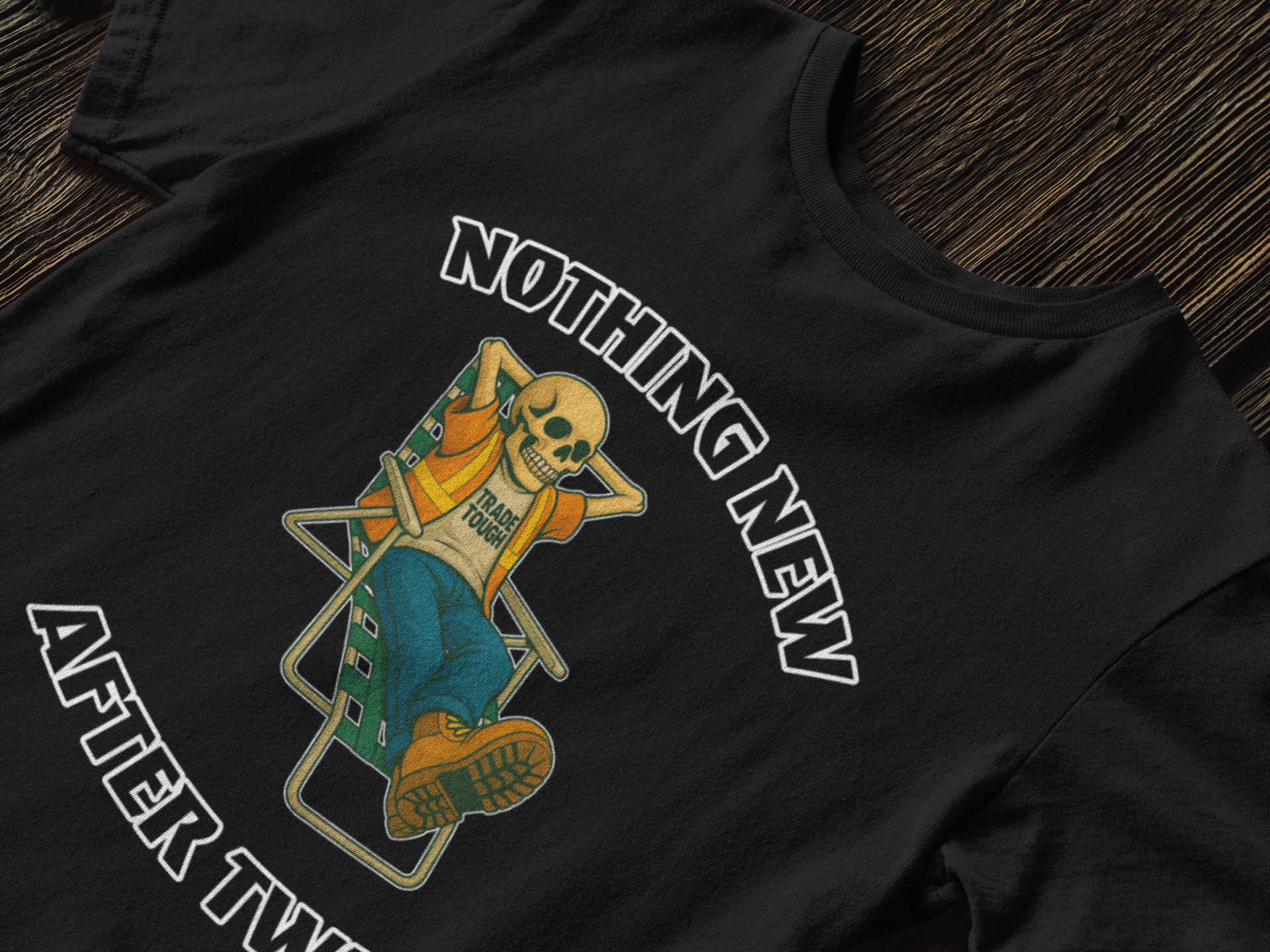 Close-up of a graphic tee showing a skeleton in a chair, arms behind head, with bold arched text

