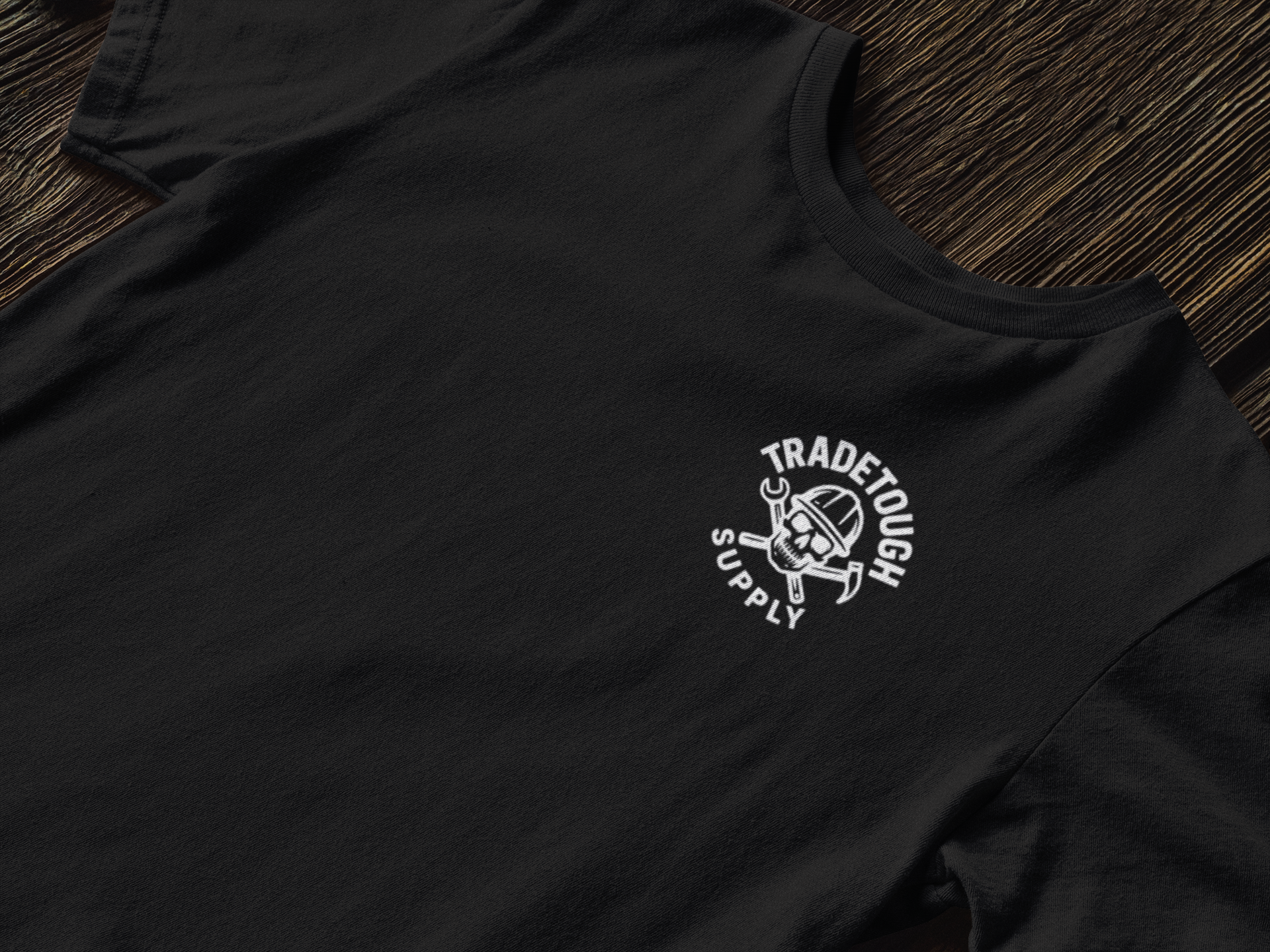 Black t-shirt with a white logo on a wooden surface