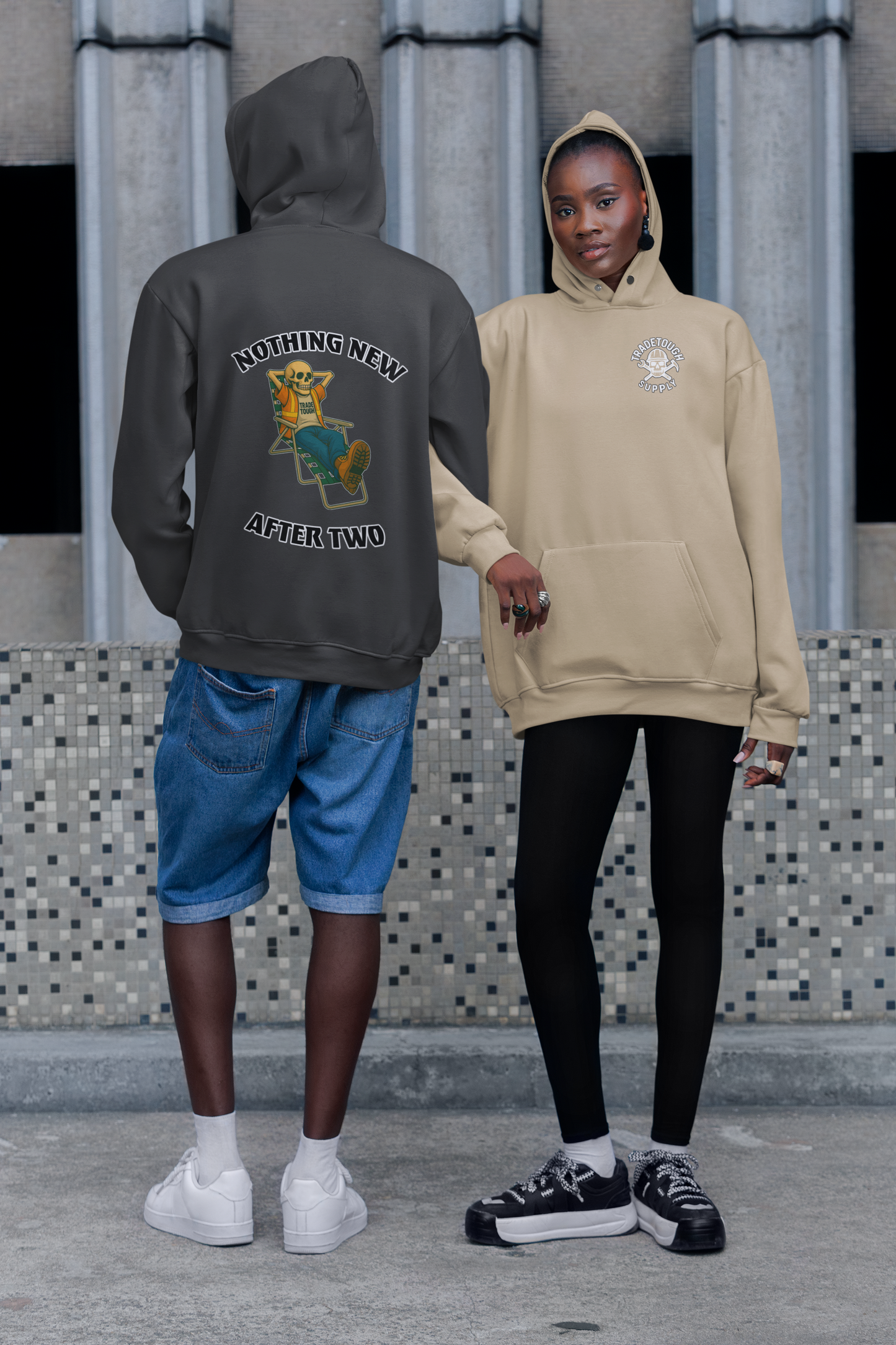 Two people wearing hoodies with visible branding against a tiled wall.